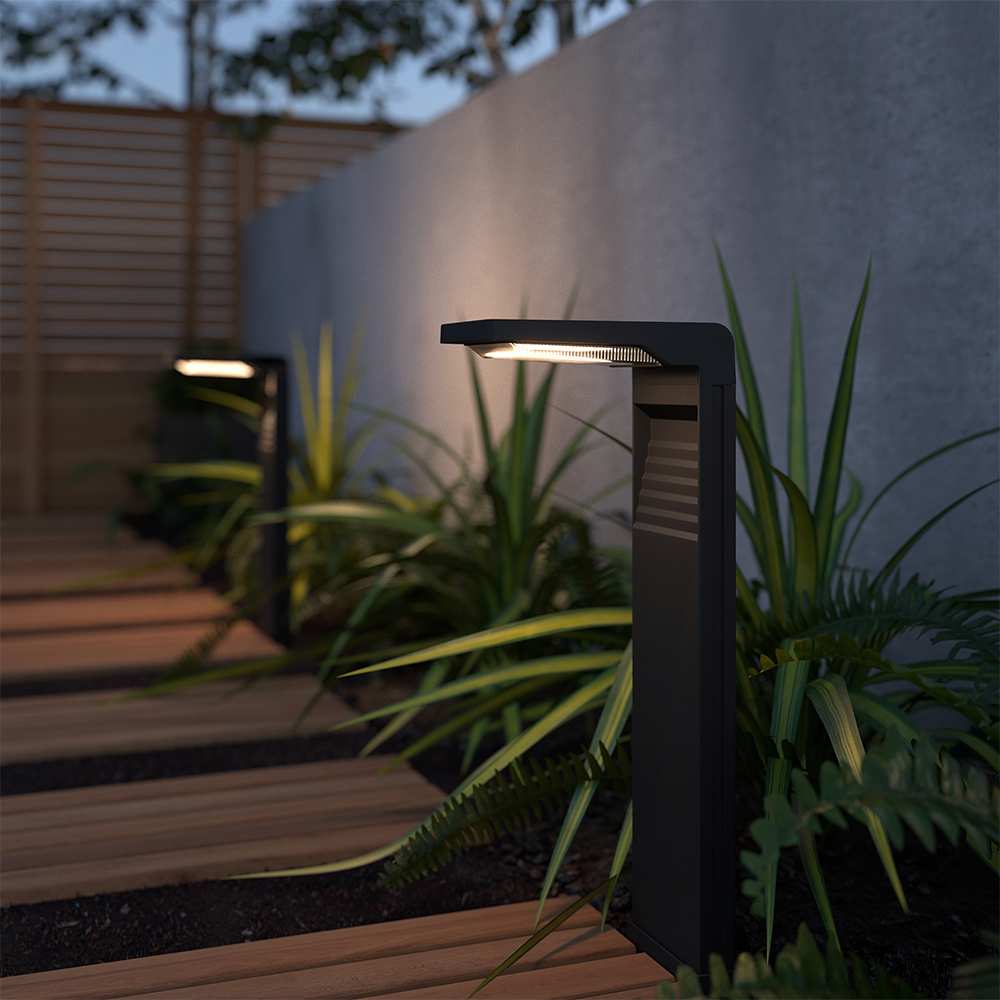 Solar-Gartenlampe mit eckigem Leuchtkopf auf Holzterrasse neben Pflanzen


