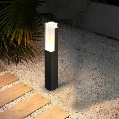 Einzelne LED-Wegeleuchte mit schwarzem Korpus und hellem Licht auf Steinweg