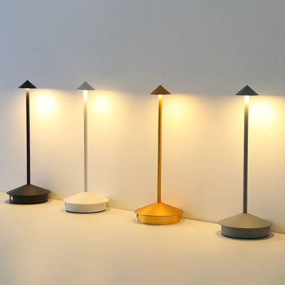 Vier schmale LED-Tischlampen in Schwarz, Gold und Grau leuchten nebeneinander

