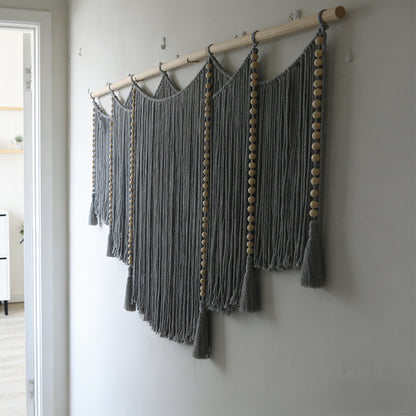 Macramé wall hanging with intricate fringes and wooden beads